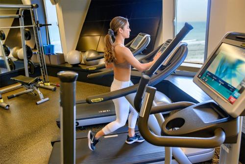 a woman running on a treadmill in a gym at Carlton Tel Aviv Hotel – Luxury on the Beach in Tel Aviv