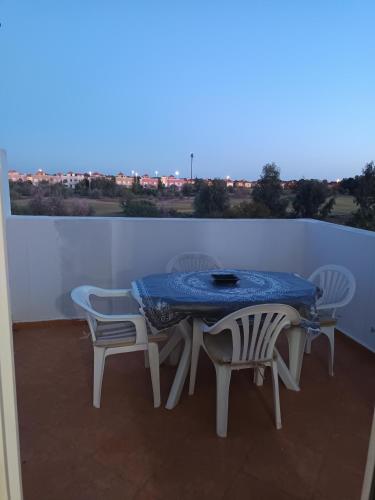 a table and chairs on a balcony with a blue table and chairs at Appartement dans Résidence avec piscine Marina P13 in Saidia 