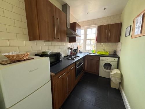 a kitchen with wooden cabinets and a washer and dryer at Silverdale Holiday Apartments in Eastbourne