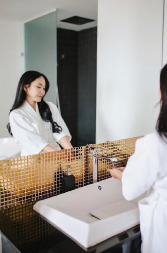 a woman standing in front of a bathroom mirror at NANEE Phra Singh in Chiang Mai
