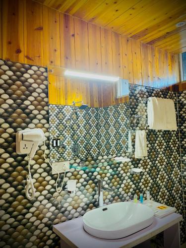 a bathroom with a sink and a stone wall at Easton Blue Hotel in Ilām