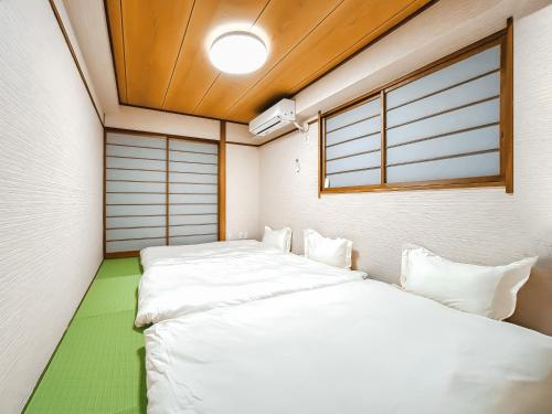 two beds in a small room with a window at YayoiHotel in Tokyo