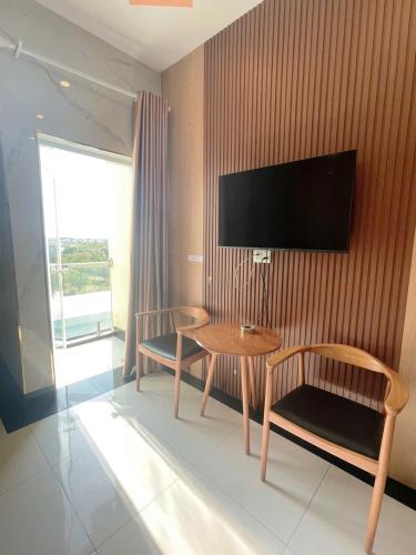 a living room with a table and a tv on a wall at Khách Sạn Sapphire in Gò Công