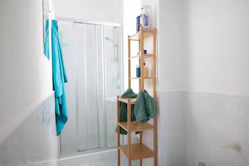 a bathroom with a wooden shelf next to a shower at Gin Mare House in Cefalù