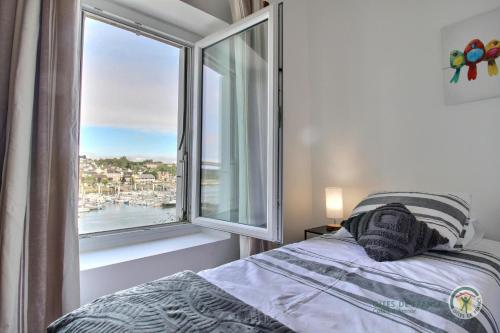 une chambre avec un lit et une grande fenêtre dans l'établissement La maison du pont, à Trédarzec