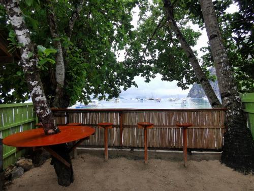 a table sitting under a tree with a view of the water at Rosie's Beach House El Nido in El Nido