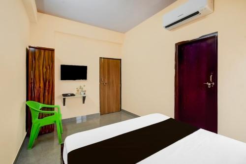 a bedroom with a bed and a green chair at Hotel O Blue Petals in Hyderabad