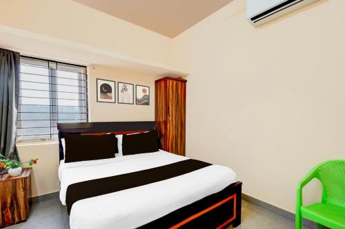 a bedroom with a bed and a green chair at Hotel O Blue Petals in Hyderabad