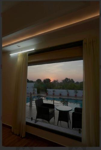 a room with a large window with a table and chairs at Farm retreat in Jaipur