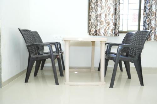 three chairs and a white table in a room at Newly Built Spacious and luxurious 4BHK apartment in Tirupati with Fully Functional Kitchen, Wifi, and Ample space for car Parking in Tirupati