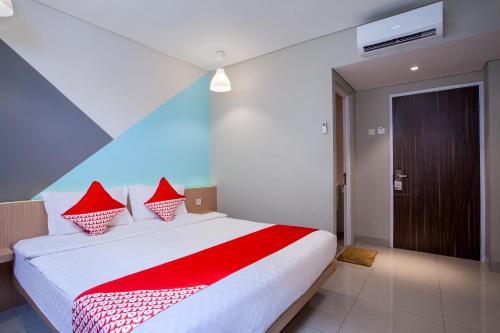 a bedroom with a large white bed with red pillows at Flagship 101 Apple Platinum in Jakarta