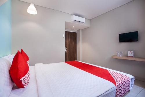 a bedroom with a white bed with red pillows at Flagship 101 Apple Platinum in Jakarta
