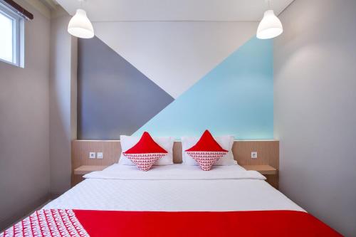 a red and white bed with red pillows on it at Flagship 101 Apple Platinum in Jakarta