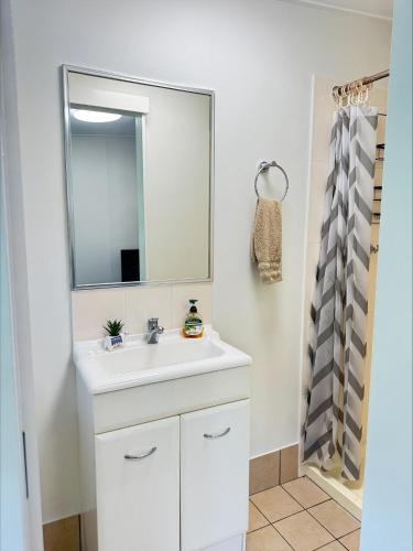 a white bathroom with a sink and a mirror at Haven39 in Bayview Heights
