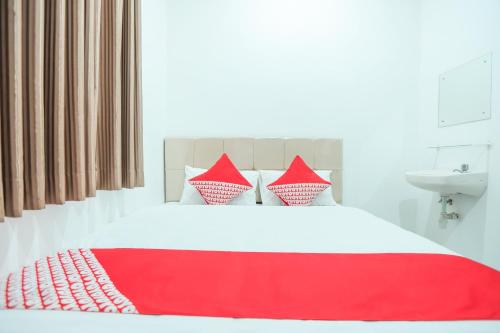 a bed with red and white pillows and a sink at Hotel O near Bundaran HI formerly Harmoni Residence in Jakarta