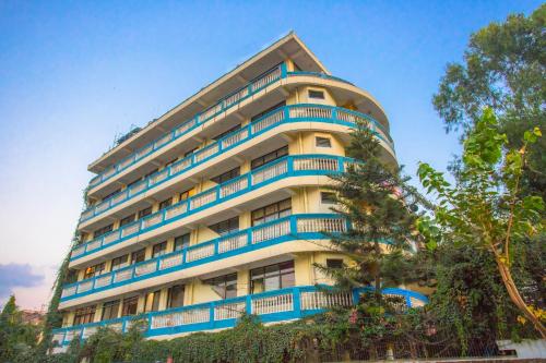 a tall apartment building with blue balconies at OYO 232 Hotel Titanic Pvt Ltd in Bālāju