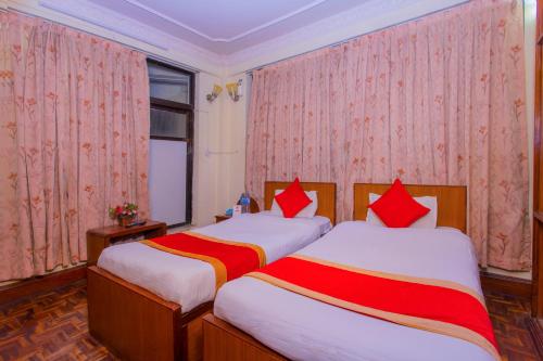 two beds in a room with red and white sheets at OYO 232 Hotel Titanic Pvt Ltd in Bālāju