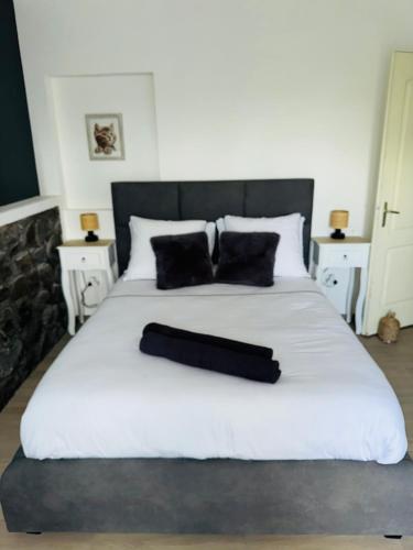 a large white bed with two black pillows on it at LaKaz à Eva in Cilaos