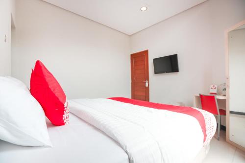 a bedroom with a white bed with red pillows at Hotel O Cempaka Place Homestay in Jakarta