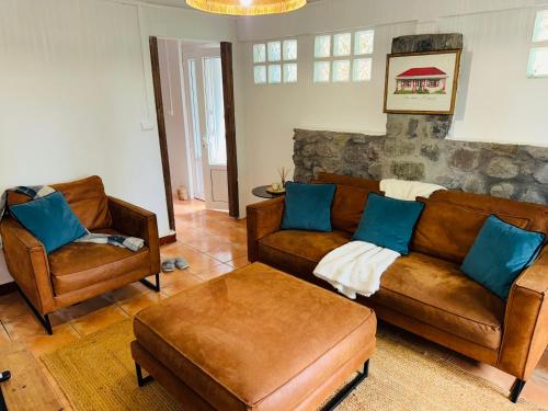 a living room with brown leather couches and blue pillows at LaKaz à Eva in Cilaos