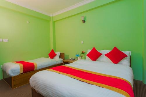 two beds in a room with green walls and red pillows at Waling Fulbari Guest House in Bālāju