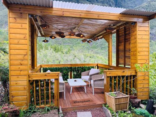 a wooden pergola with a table and chairs on a deck at LaKaz à Eva in Cilaos