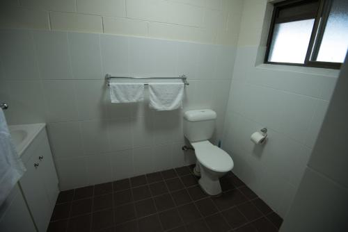 a white bathroom with a toilet and a window at Settlers Inn in Port Macquarie
