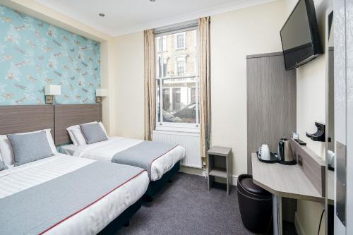 a hotel room with two beds and a television at OYO Bakers Hotel London Victoria in London