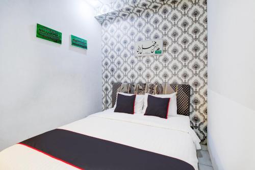 a bedroom with a white bed and a wall at Hotel O Jalan Jenderal Sudirman Near Imam Bonjol Square in Padang