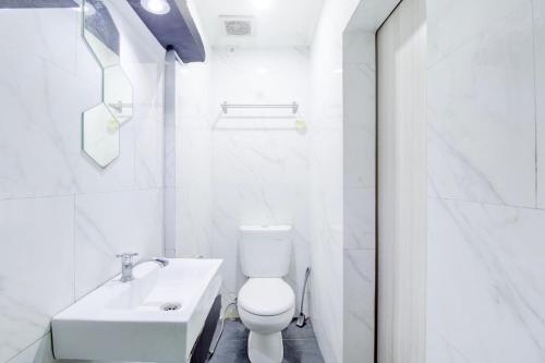 a white bathroom with a toilet and a sink at Hotel O Jalan Jenderal Sudirman Near Imam Bonjol Square in Padang