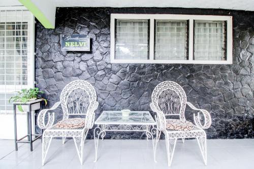 two chairs and a table in front of a stone wall at Hotel O Jalan Jenderal Sudirman Near Imam Bonjol Square in Padang