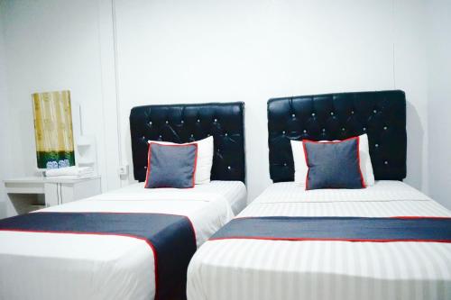 two beds sitting next to each other in a room at Hotel O Padang City Center Near Pantai Padang Formerly Hotel Siti Nurbaya in Padang