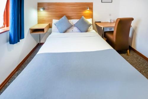 a bedroom with a large white bed and a desk at Arinza Hotel, London Ilford in Ilford