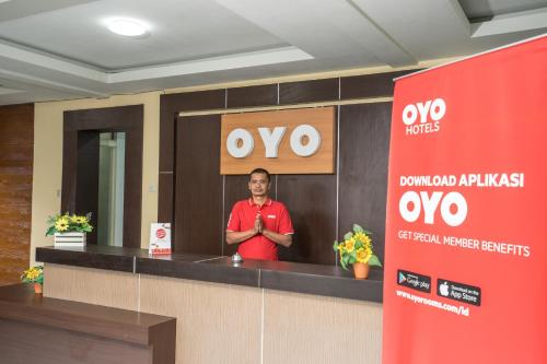 a man standing behind a counter in a room at Hotel O Central Batu Near Jatim Park 3 Formerly Bunga Matahari Hotel in Batu