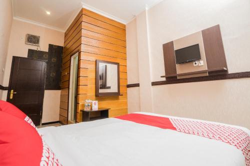 a bedroom with a bed and a tv on the wall at Hotel O Central Batu Near Jatim Park 3 Formerly Bunga Matahari Hotel in Batu