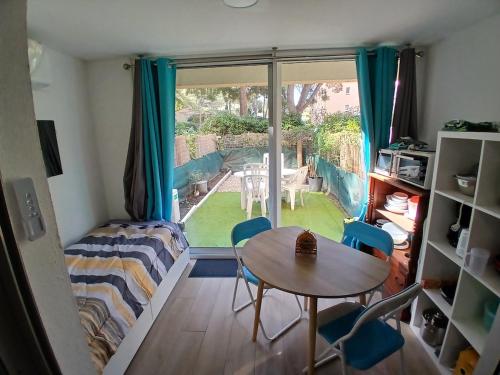 un salon avec une table et des chaises et une fenêtre dans l'établissement Le Lagos 3 min mer clim Jardin parking, à Saint-Mandrier-sur-Mer