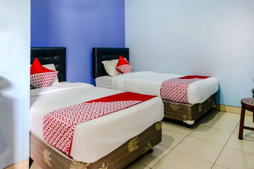 two beds in a room with blue walls and red pillows at Hotel O Guest House Amalia Malang in Malang