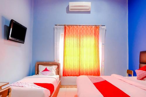 a room with two beds and a window with a colorful curtain at Hotel O Guest House Amalia Malang in Malang