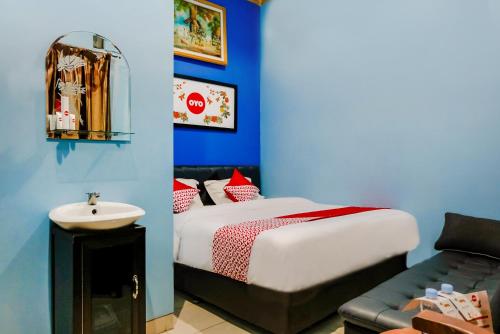 a bedroom with a bed and a sink and a couch at Hotel O Guest House Amalia Malang in Malang