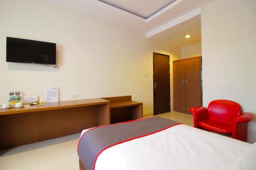 a hotel room with a bed and a red chair at Collection O Pasteur Near Paris Van Java Mall Formerly Sweet Karina in Bandung