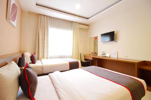 a hotel room with two beds and a television at Collection O Pasteur Near Paris Van Java Mall Formerly Sweet Karina in Bandung
