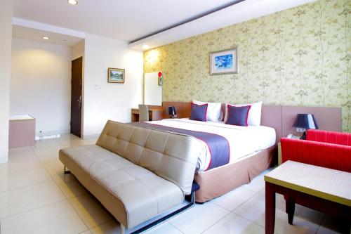 a bedroom with a large bed and a couch at Collection O Pasteur Near Paris Van Java Mall Formerly Sweet Karina in Bandung