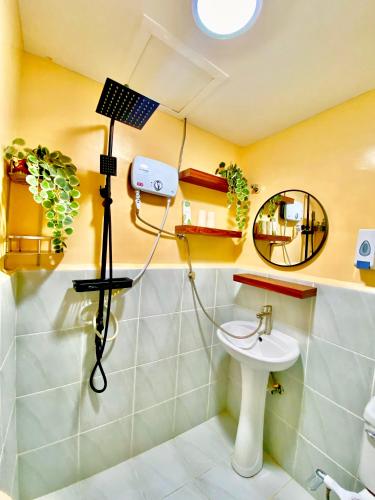 a bathroom with a shower with a sink and a mirror at Timbi Suites Mactan in Lapu Lapu City