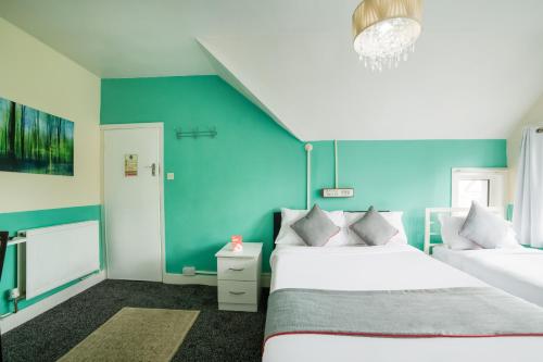 a bedroom with two beds and a blue wall at Devine Beach Hotel, Westcliff Southend-On-Sea in Southend-on-Sea