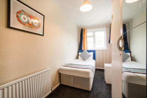 a small room with two beds and a window at Devine Beach Hotel, Westcliff Southend-On-Sea in Southend-on-Sea