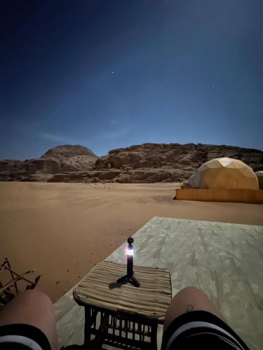 a person sitting on a table with a flashlight on the beach at Moon Rum LuxuryCamp in Wadi Rum