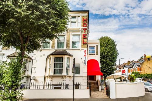 a large white building with a red awning at OYO London Guest House in London