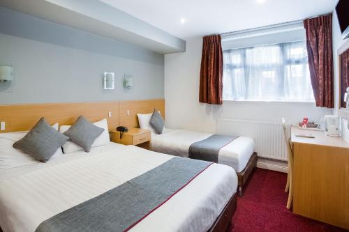 a hotel room with two beds and a desk at OYO London Guest House in London