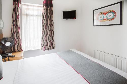 a bedroom with a bed and a tv on the wall at OYO London Guest House in London
