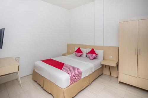 a bedroom with a bed with two red pillows at Hotel O Lapan Lapan in Banjarmasin